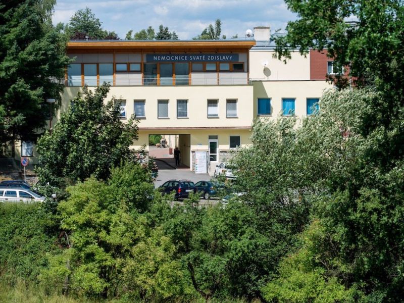Здание Больницы Святой Здиславы в Мостиште среди зелени, вид с улицы